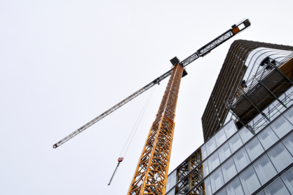 A crane standing tall above a modern constructions site, needing advanced rigging courses